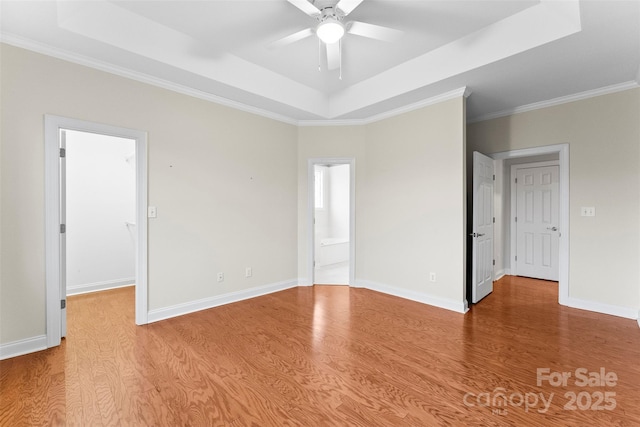 unfurnished room with ceiling fan, light wood-type flooring, and a tray ceiling