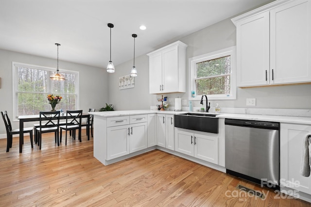 kitchen featuring pendant lighting, sink, dishwasher, white cabinetry, and kitchen peninsula