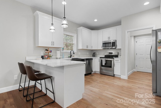 kitchen with pendant lighting, white cabinetry, stainless steel appliances, and kitchen peninsula