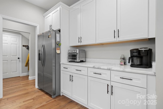 kitchen featuring white cabinetry, stainless steel refrigerator with ice dispenser, light stone counters, and light hardwood / wood-style floors