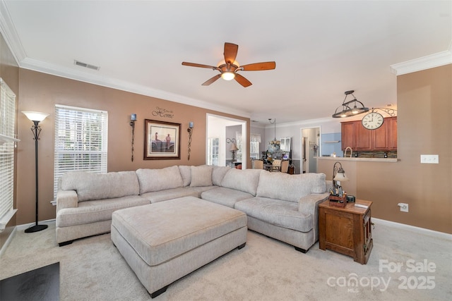 living area with ornamental molding, ceiling fan, light colored carpet, and baseboards