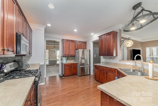 kitchen featuring appliances with stainless steel finishes, a sink, light wood finished floors, backsplash, and light countertops