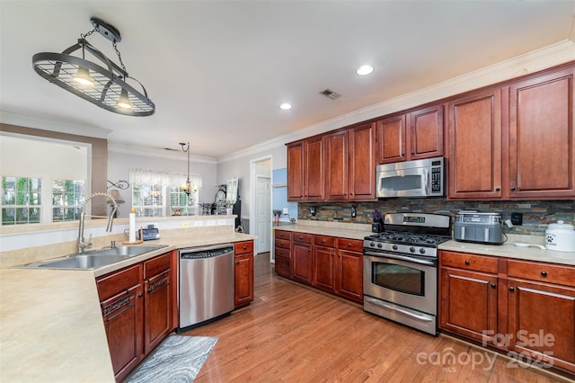 kitchen featuring appliances with stainless steel finishes, a sink, light countertops, ornamental molding, and recessed lighting