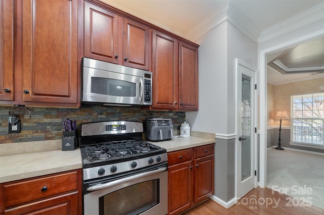 kitchen featuring stainless steel appliances, crown molding, light countertops, tasteful backsplash, and baseboards