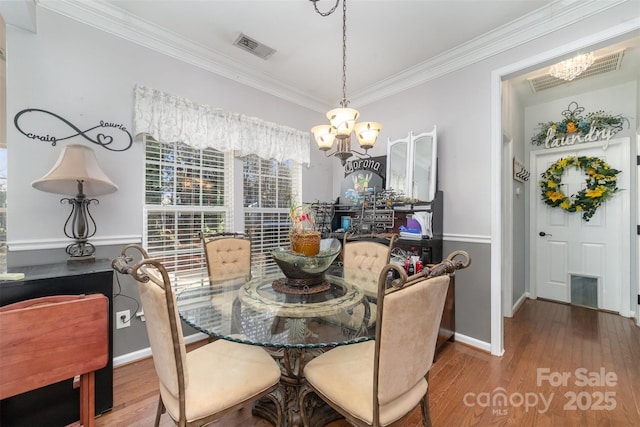 dining area with a chandelier, wood finished floors, ornamental molding, and baseboards
