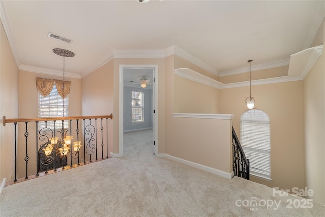 hall with an upstairs landing, carpet floors, ornamental molding, a chandelier, and baseboards