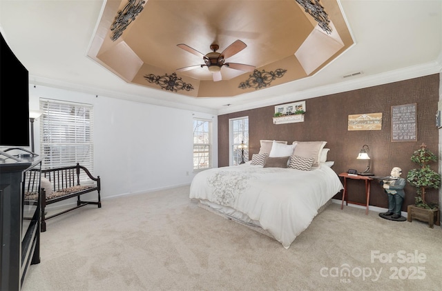 bedroom featuring a raised ceiling, light colored carpet, baseboards, crown molding, and a ceiling fan