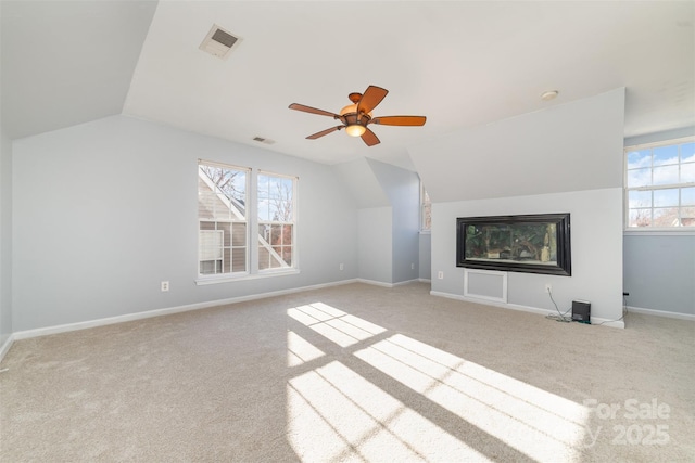 unfurnished living room with carpet floors, vaulted ceiling, plenty of natural light, baseboards, and a ceiling fan