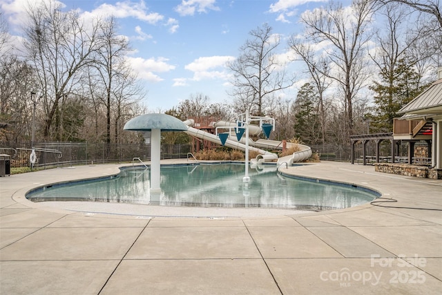 community pool with a water slide, fence, and a patio