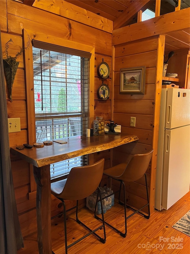 dining area with wooden walls and light hardwood / wood-style flooring