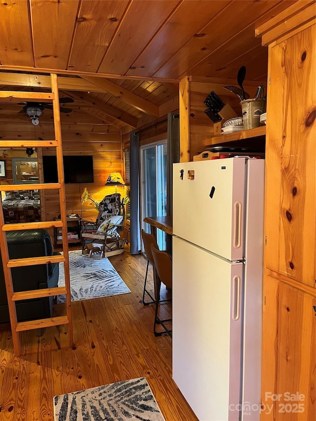 kitchen featuring wood walls, vaulted ceiling, wooden ceiling, white refrigerator, and hardwood / wood-style flooring