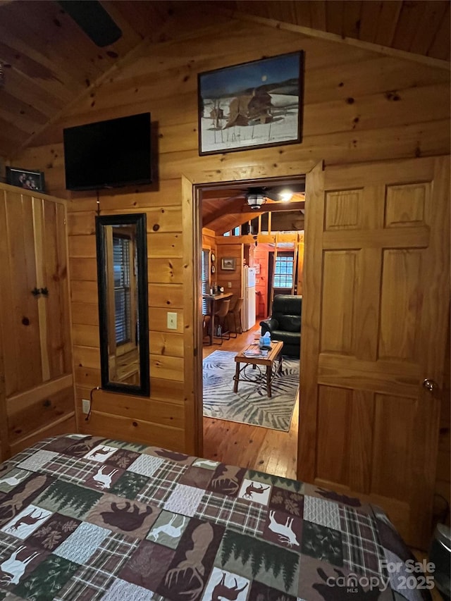 bedroom featuring wood-type flooring, lofted ceiling, and wooden walls