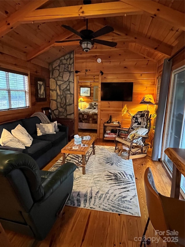 living room featuring hardwood / wood-style floors, wooden walls, vaulted ceiling with beams, ceiling fan, and wooden ceiling