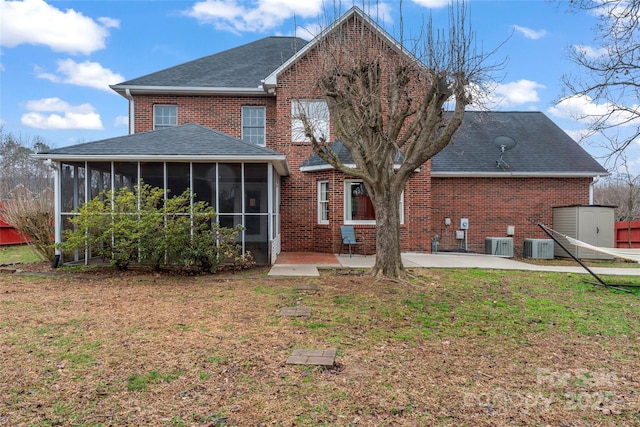 rear view of house with central AC, a patio, a sunroom, and a lawn