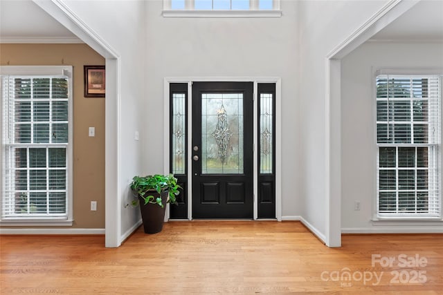 entryway with crown molding and light wood-type flooring