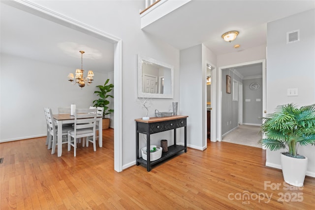 corridor with a notable chandelier and light hardwood / wood-style flooring