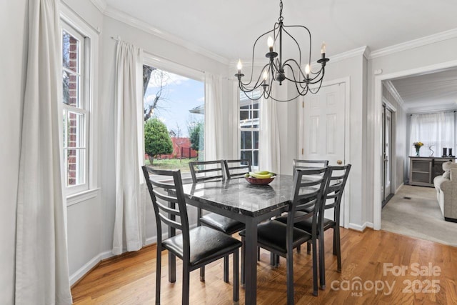 dining space featuring crown molding, a chandelier, and light hardwood / wood-style flooring