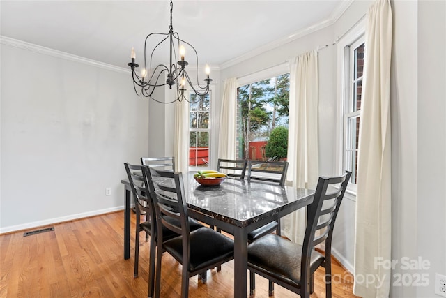 dining space featuring crown molding, light hardwood / wood-style flooring, and a notable chandelier