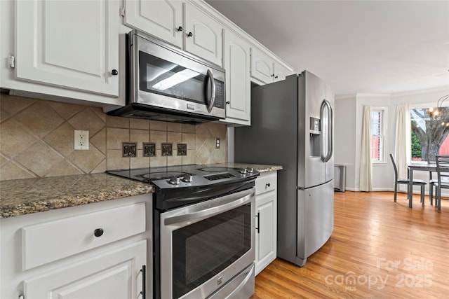 kitchen featuring dark stone countertops, appliances with stainless steel finishes, backsplash, and white cabinets