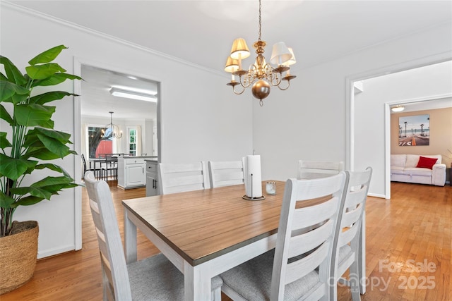 dining room with crown molding, light hardwood / wood-style floors, and a chandelier