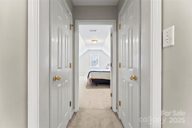 corridor featuring lofted ceiling and light carpet