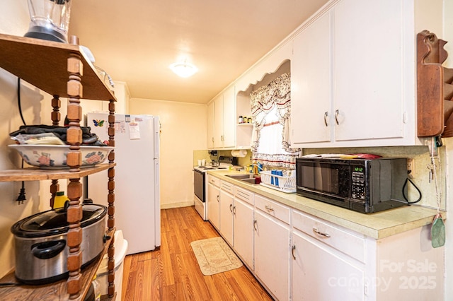 kitchen featuring white cabinetry, sink, white appliances, and light hardwood / wood-style floors