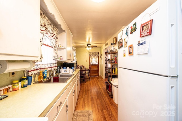 kitchen with sink, white cabinetry, wood-type flooring, white refrigerator, and ceiling fan