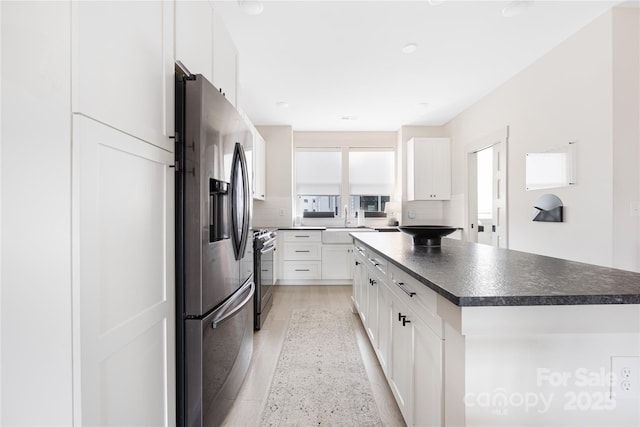 kitchen with white cabinetry, sink, stainless steel appliances, and a center island