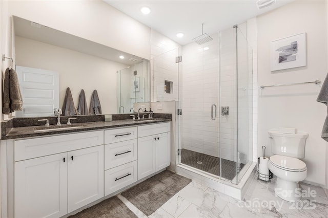 bathroom featuring vanity, a shower with door, and toilet