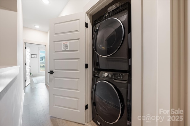 laundry room with light hardwood / wood-style flooring and stacked washing maching and dryer