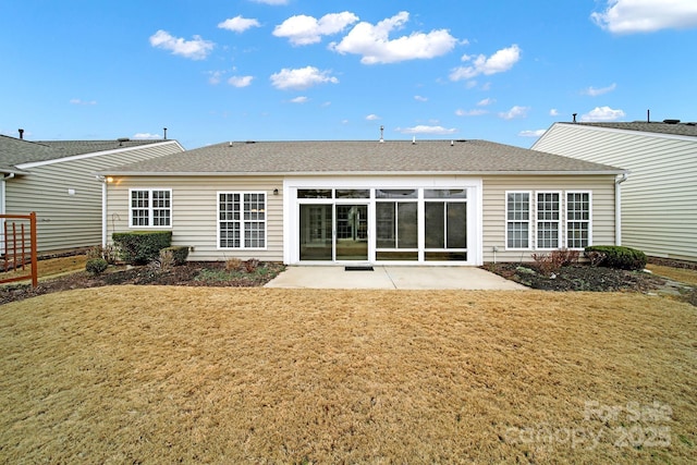 back of property featuring a lawn, roof with shingles, and a patio