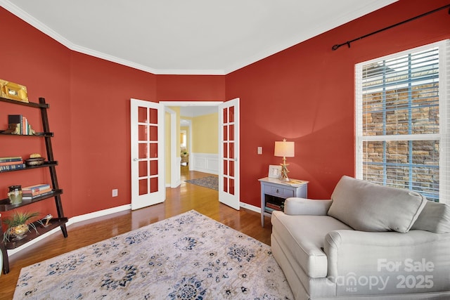 sitting room featuring french doors, ornamental molding, baseboards, and wood finished floors
