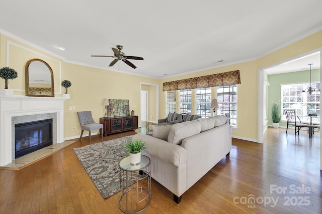 living area with baseboards, ornamental molding, ceiling fan, and wood-type flooring