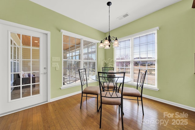 dining space with baseboards, a notable chandelier, visible vents, and wood-type flooring