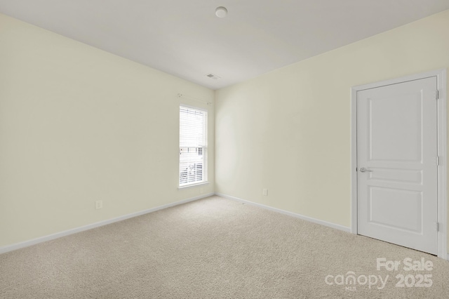 empty room featuring baseboards and light colored carpet
