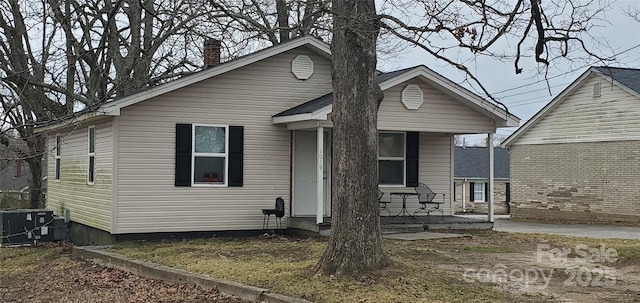 bungalow-style house with a porch and central AC unit