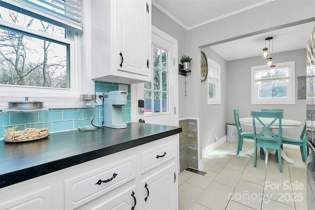 kitchen featuring a healthy amount of sunlight, decorative light fixtures, crown molding, and white cabinets