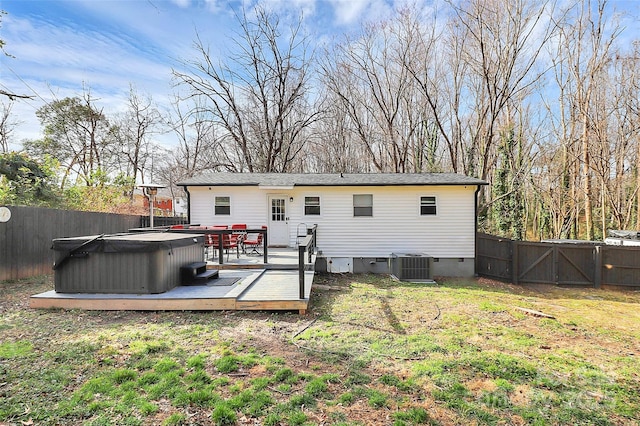 rear view of property featuring a hot tub, a wooden deck, a lawn, and central air condition unit