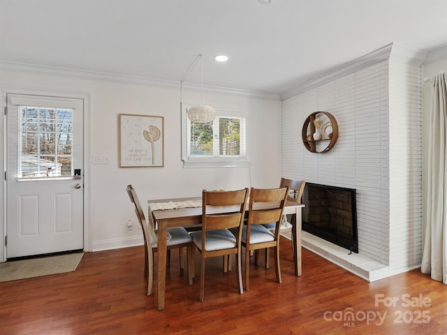 dining area with baseboards, wood finished floors, crown molding, a fireplace, and recessed lighting