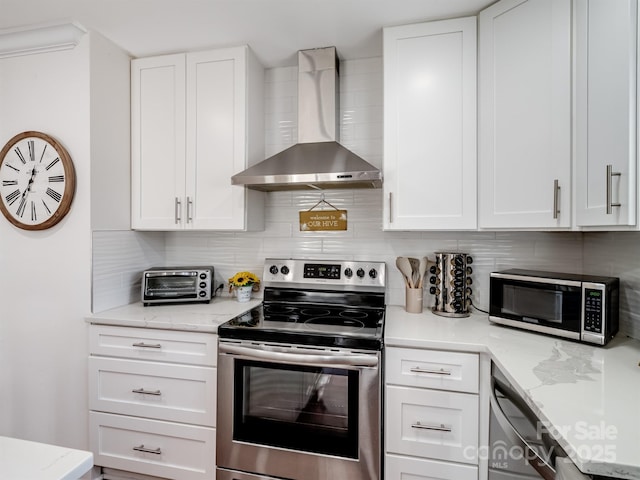 kitchen featuring a toaster, wall chimney range hood, appliances with stainless steel finishes, and decorative backsplash