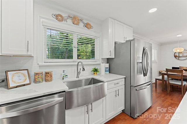 kitchen with stainless steel appliances, white cabinetry, a sink, and backsplash