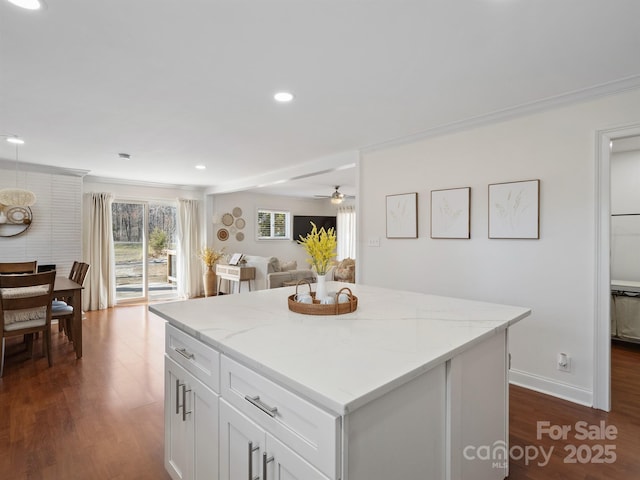 kitchen featuring light stone countertops, white cabinetry, dark wood finished floors, and a center island