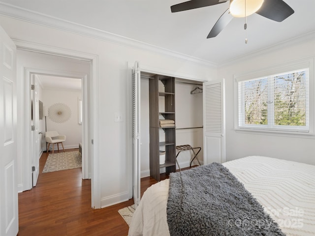 bedroom featuring dark wood-style flooring, a ceiling fan, baseboards, ornamental molding, and a closet