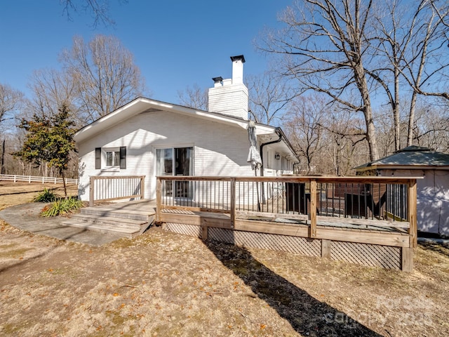 rear view of property featuring a chimney, fence, and a wooden deck