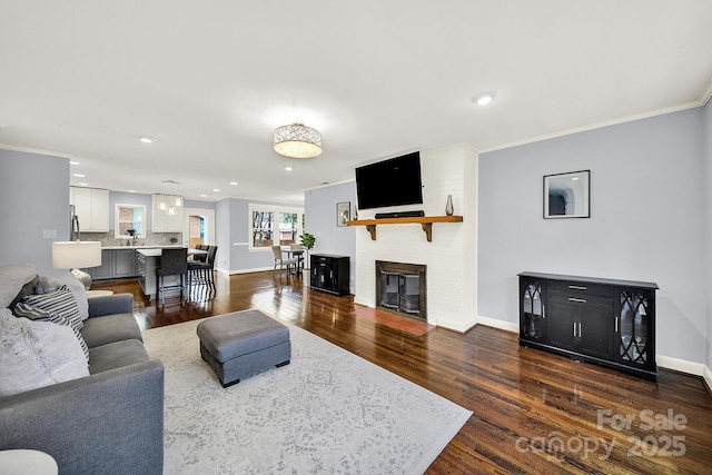 living room with ornamental molding, a brick fireplace, and dark wood-type flooring