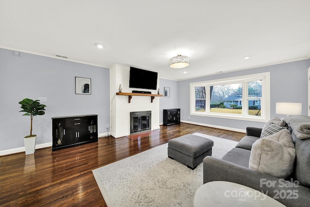 living room with crown molding, dark hardwood / wood-style floors, and a large fireplace