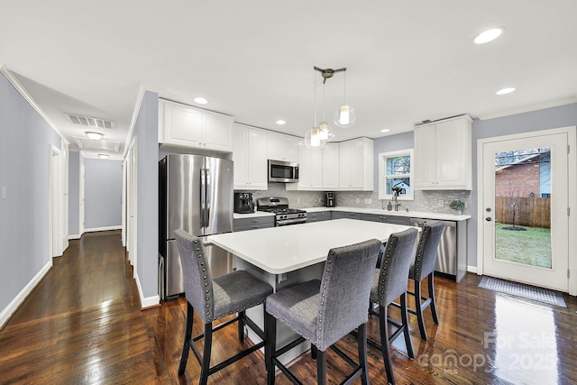 kitchen with pendant lighting, white cabinetry, stainless steel appliances, and a center island