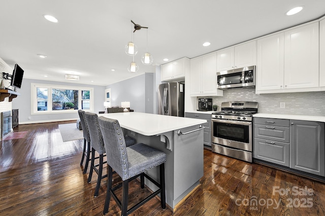 kitchen featuring gray cabinets, white cabinets, pendant lighting, stainless steel appliances, and backsplash