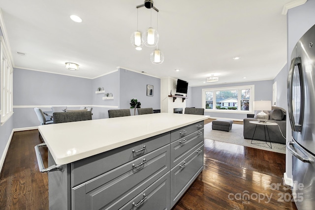 kitchen featuring pendant lighting, dark wood-type flooring, gray cabinets, stainless steel fridge, and a center island