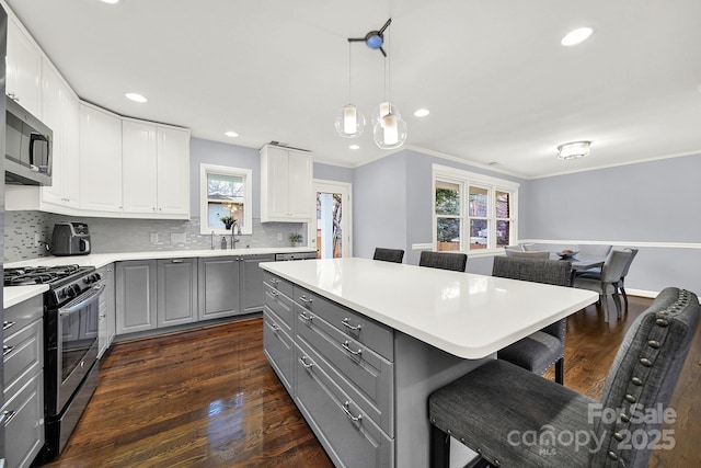 kitchen featuring hanging light fixtures, stainless steel appliances, a center island, and white cabinets